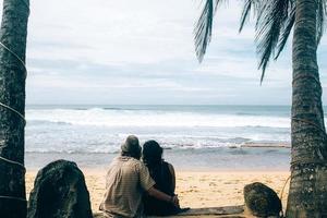 casal sentado sob palmeiras foto