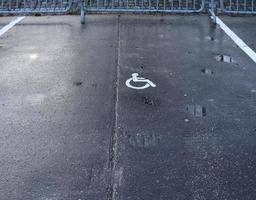lugares de estacionamento para clientes com mobilidade condicionada. estacionamento com placa pintada de cadeira de rodas. foto