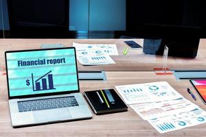 apresentação de relatório financeiro no laptop de exibição e papelada na mesa na sala de reuniões foto
