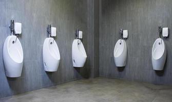 banheiro masculino com mictórios de porcelana branca na fila foto