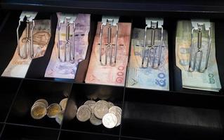 notas de banco tailandesas e moedas estão na máquina de caixa