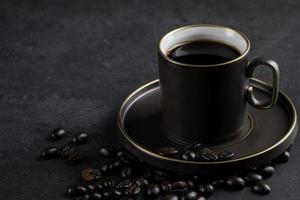 o café está quente em uma xícara de café marrom e os grãos de café são colocados um pouco. ambiente aconchegante e leve em um fundo escuro com área de fotocópia. foto