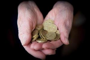 mãos idosas segurando moedas da libra esterlina