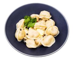 pelmeni cozido decorado com salsa na tigela foto