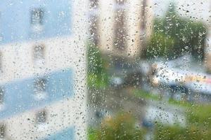 gotas de chuva na vidraça e cidade turva foto