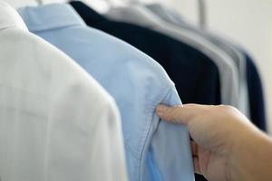 homem está escolhendo a camisa no quarto de roupas em casa. foto