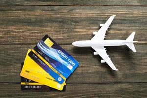 cartão de crédito e modelo de avião na mesa de madeira foto