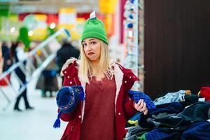 jovem mulher escolhendo chapéu no shopping foto