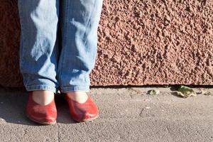 pernas em jeans azul e sapatos vermelhos foto