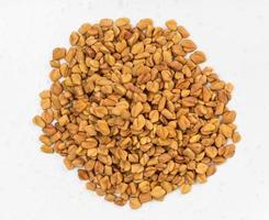 pilha de sementes de feno-grego inteiras close-up em cinza foto
