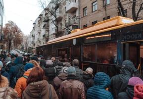 muitas pessoas não identificadas estão esperando o transporte da cidade no ponto de ônibus foto