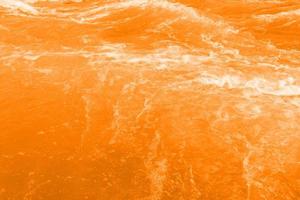desfocar a textura de superfície de água calma transparente de cor laranja transparente turva com respingo, bolha. fundo de ondulação de água laranja brilhante. superfície da água na piscina. água de bolha laranja, respingo. foto