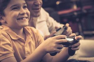 close-up de menino feliz jogando videogame com seu pai em casa. foto