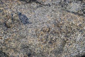 fundo de textura de rocha de granito cinza cru. fragmento de parede de pedra natural foto