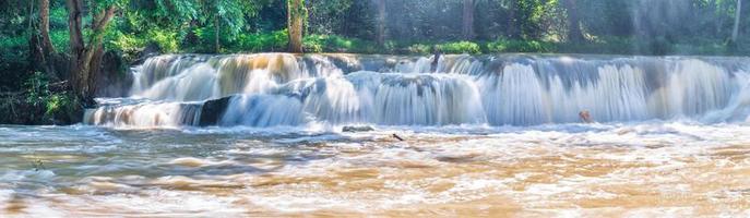 a água cai na floresta tropical com rocha e árvore foto