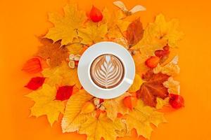 xícara de café com leite em moldura de grinalda de folhas de outono secas foto