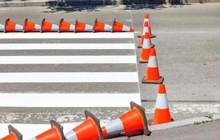 marcações rodoviárias listradas de uma passagem de pedestres na vedação de cones de trânsito. foto