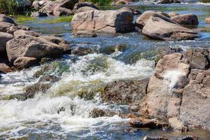 fluxo de água tempestuosa e rápida entre enormes pedras de pedra. foto