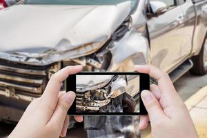 mulher usando smartphone móvel tirando foto de acidente de carro danificado para seguro