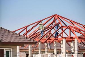 trabalhadores de solda instalando estrutura de armação de aço do telhado da casa no canteiro de obras foto