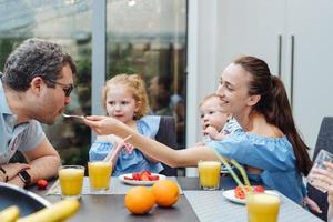 família feliz tomando café da manhã com frutas frescas foto