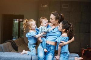 mãe, duas filhas e um filho pequeno no sofá foto