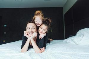 mãe e duas filhas se divertem na cama foto