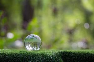 globo planeta vidro na floresta verde com luzes da natureza bokeh. dia Mundial do Meio Ambiente. conceito de conservação do meio ambiente, proteger a ecologia da terra e a vida ecológica ambiental com espaço de cópia foto