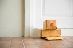 caixa de papelão perto da porta no chão. compras online, caixas entregues à sua porta. fácil de roubar quando ninguém está em casa. pacote em caixa de papelão na porta. serviço de entrega foto