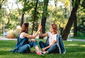 amigas felizes levantando as mãos dando mais cinco no parque da cidade foto