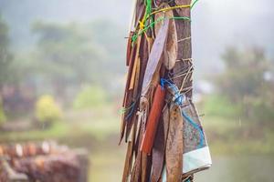 etiquetas de oração amarradas a um poste na ponte na vila da mina de pilok na cidade de kanchanaburi na tailândia. mina de pilok a antiga mina perto da fronteira tailandesa-mianmar foto