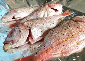 cozinhar peixe fresco em papel alumínio. vista superior e close-up. frutos do mar saudáveis. preparação de refeições dietéticas. foto