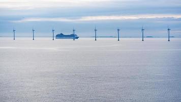 balsa perto do parque eólico offshore no crepúsculo da manhã foto