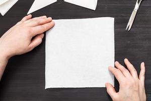 mãos seguram um pedaço de papel em branco na mesa foto