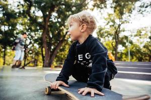 jovem sentado no parque em um skate. foto