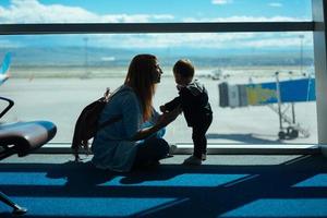 garotinho e sua mãe sentados em um aeroporto foto