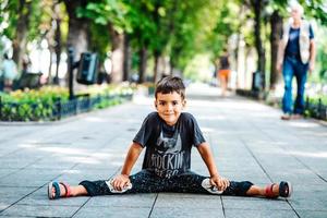 menino criança sorridente feliz sentado no caminho em um parque. foto