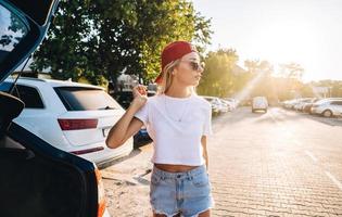 mulher jovem e bonita no estacionamento perto do carro foto