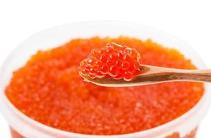 pequena colher de pau com caviar vermelho sobre o recipiente foto