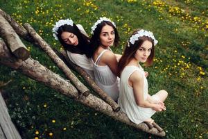 três garotas encantadoras perto de uma casa de madeira foto