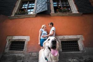 casal e cachorro em uma parede vermelha foto