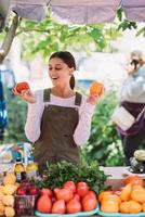 jovem vendedora segurando tomates caseiros nas mãos foto