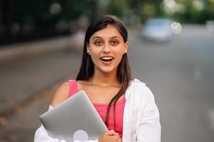 uma jovem segurando um laptop olha para a câmera foto