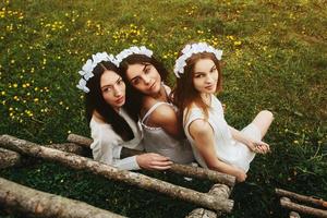 três garotas encantadoras perto de uma casa de madeira foto