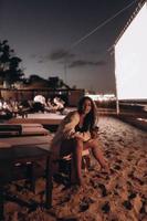 jovem está sentada na cadeira na praia à noite foto
