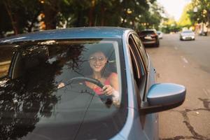 linda mulher sorridente dirigindo carro, garota sentada no automóvel foto