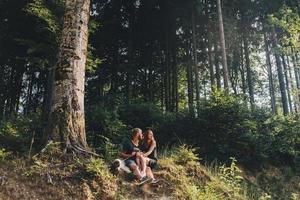 lindo casal sentado em uma floresta perto da árvore foto