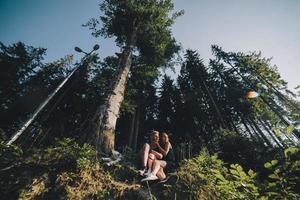 lindo casal sentado em uma floresta perto da árvore foto