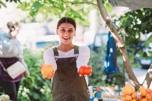 jovem vendedora segurando tomates caseiros nas mãos foto