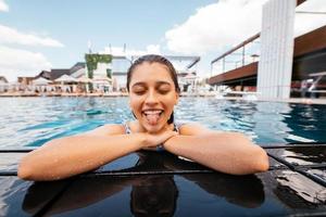 jovem descansando na beira da piscina foto